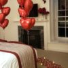 Room decorated with romantic Red heart balloons,red roses, Tea light candles and rose petals