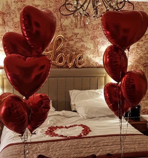 Valentine's day florist: Bedroom decoration with red rose petals and Red Heart Balloons