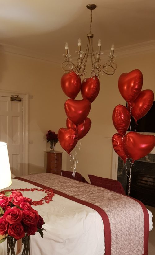 Room decorated with red rose petals,Red heart balloons and roses